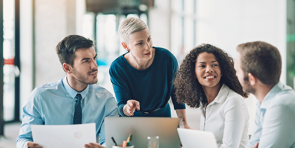 4 people sit at table talking about work