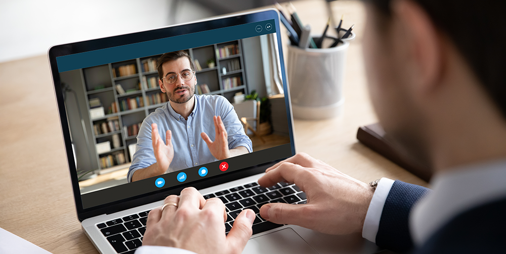 Two men have a video conversation on a laptop.