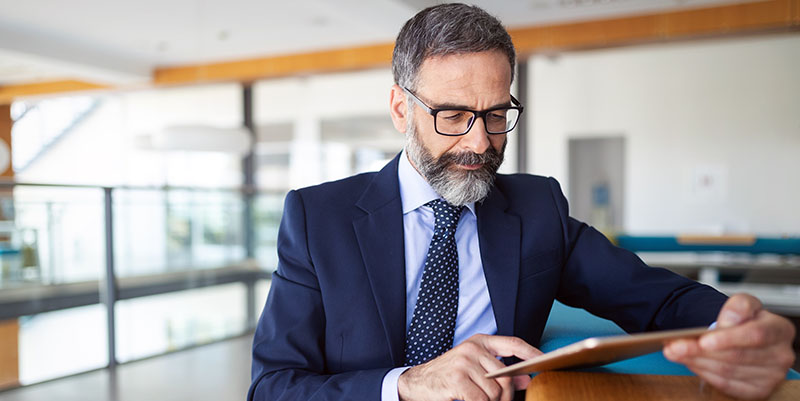 Executive completes training on his tablet computer while sitting at a table.