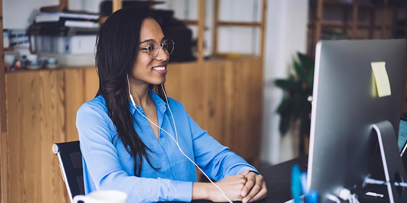 Woman sits at desk and watches role-specific training that's beneficial to her growth.