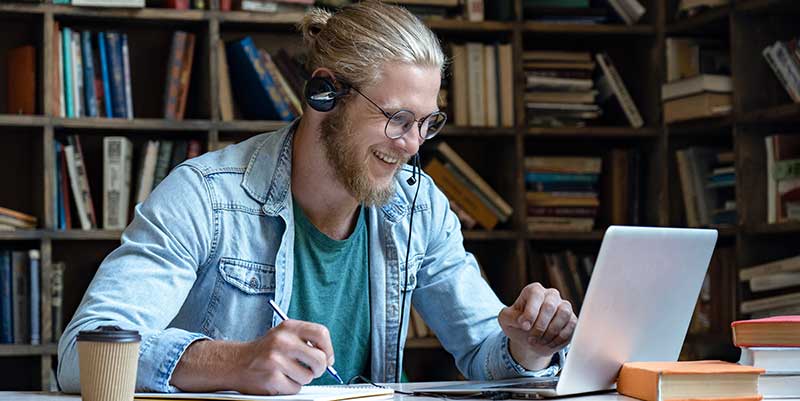 Man sits in office library and takes online training.