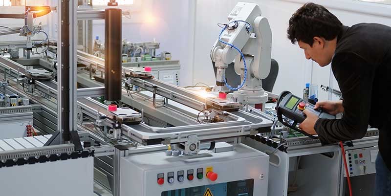 Man works on robot in Smart manufacturing plant.